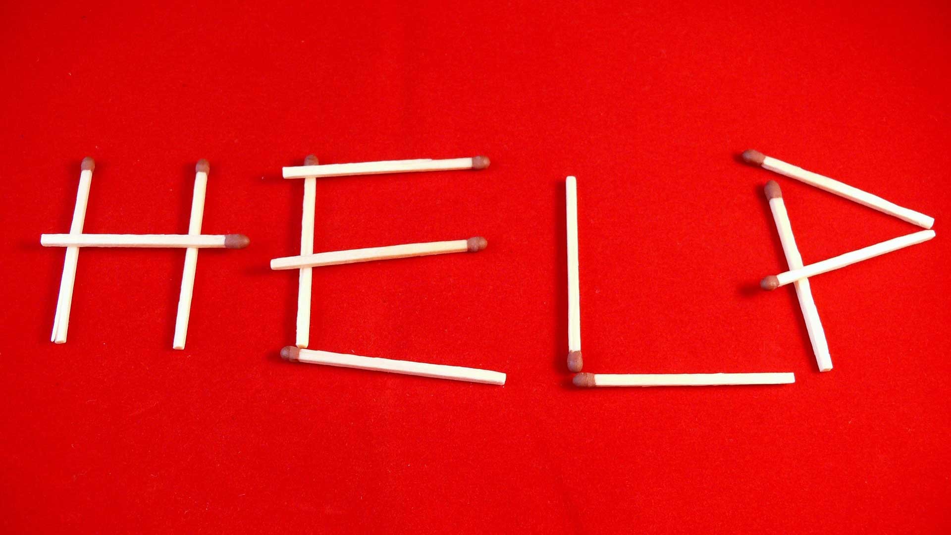 Word help written with matchsticks on a red background